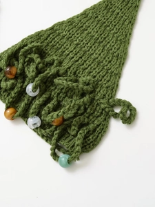 Close-up of green hand-knitted swimwear fabric featuring brown and clear bead details