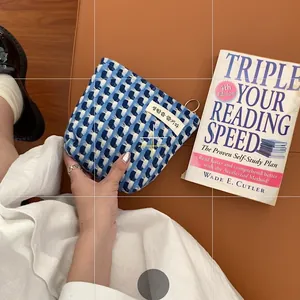 Gros plan d'une trousse tissée bleu et blanc avec étiquette coréenne tenue à la main