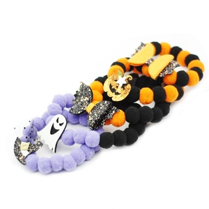 Colorful Halloween pet collars with plush balls and festive charms on white background