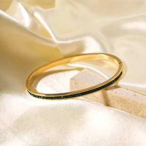 18K gold plated stainless steel bangle featuring emerald green zircon stones on silk