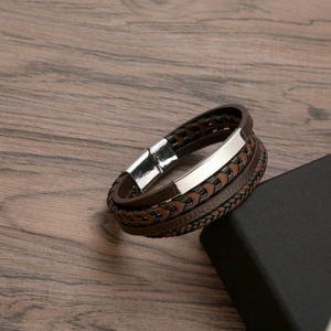 Vintage multi-layer brown and black leather bracelet with silver buckle on wood background