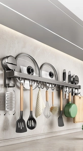 Wall-mounted gunmetal kitchen storage rack with hooks holding utensils and pot lids