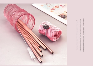 Close-up of pink heart-shaped stainless steel straws with a cleaning brush and mesh bag