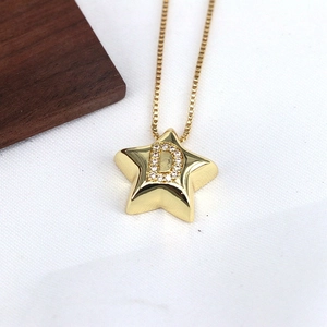 Detail of gold star pendant necklace with micro-pave cubic zirconia letter D engraving