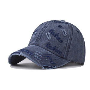 Close-up of Kindness embroidery and distressed detail on washed denim baseball cap