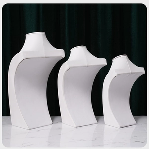 Three white leather necklace display busts in small, medium, and large sizes on marble