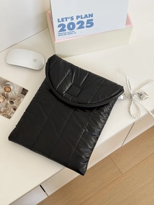 Detail der schwarzen gesteppten Laptoptasche mit Perlenherzanhänger auf Schreibtisch