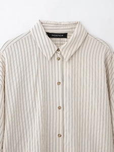 Detailed close-up of the striped shirt collar and buttons on a beige knit fabric