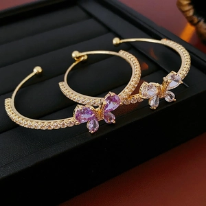 Détail macro de bracelets papillons dorés avec cristaux de zircone violets et blancs