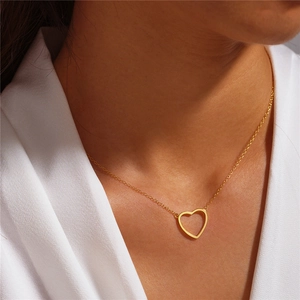 Detail showing a minimalist gold heart pendant necklace worn on a white shirt collar