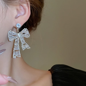 Close-up of a large silver bow earring with baguette cubic zirconia worn on model