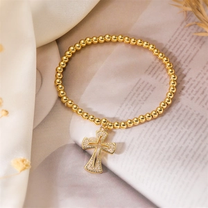 Detail of gold beaded bracelet featuring a hollow cross pendant with zircon stones