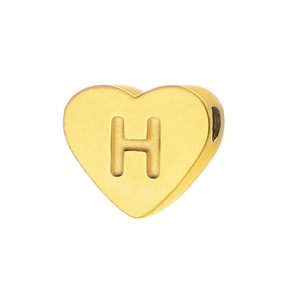 Macro detail of a heart-shaped golden bead with H engraving and side hole for jewelry DIY