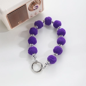 Detailed macro view of purple faux fur pompom and silver beads on a wristlet keychain