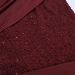 Détail du tissu bouclé bordeaux avec paillettes scintillantes sur la robe longue