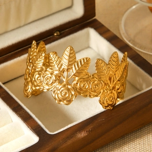 Macro shot of detailed 18K gold rose and leaf relief on a vintage stainless steel cuff