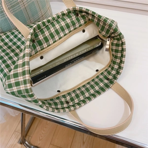 Detail view of green checkered canvas tote with inner pocket and leather handle