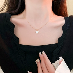 Gros plan d'un collier en titane doré avec pendentif cœur en nacre sur le cou d'un mannequin