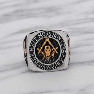 Close-up of Masonic ring with gold lettering and skull carvings on silver stainless steel
