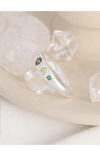 Detail of silver S925 ring featuring smokey grey, pale yellow, and emerald green zircons