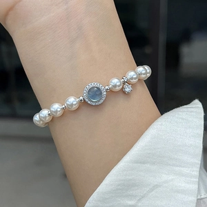 Detail showing elegant pearl bracelet with blue zircon centerpiece on woman's wrist