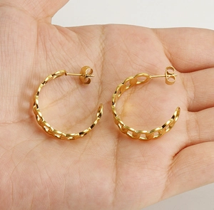 Detailed close-up of 18k gold-plated stainless steel Cuban link hoop earrings on hand