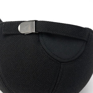 Close-up of black baseball cap's adjustable metal buckle and textured twill fabric detail