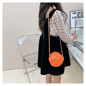Detail of round orange quilted leather girls crossbody bag with gold chain strap