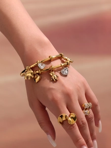 Detailed view of layered gold bracelet with elephant charms and sparkling butterfly ring
