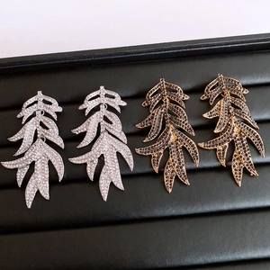 Close-up of sparkling leaf tassel earrings with rhinestones in silver and bronze colors