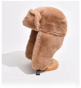 Close-up of thick plush camel faux fur winter hat with earflaps and adjustable buckle