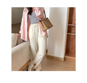 Detail of soft off-white casual pants with drawstring waist and stylish side split hems