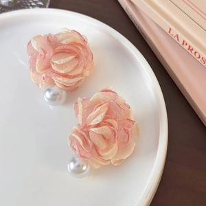 Detail of pink chiffon flower earrings with white pearls on a ceramic dish