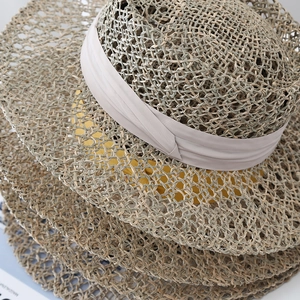 Handwoven seagrass sun hat for women featuring hollow breathable weave and wide ribbon band
