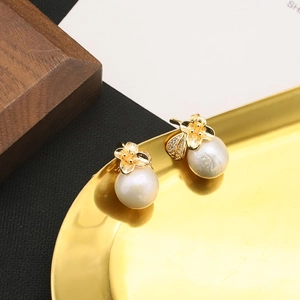 Elegant gold flower pearl earrings with micro-set zircons on a golden metal tray