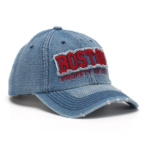 Détail d'une casquette en denim vintage avec broderie Boston rouge et bordure usée