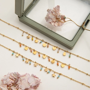 Detailed view of layered gold necklaces with heart and star pendants on white background