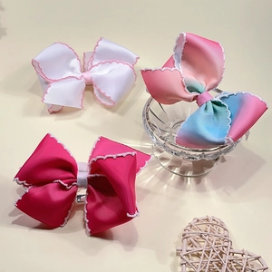Détail des barrettes nœuds en ruban gros-grain arc-en-ciel avec bords festonnés