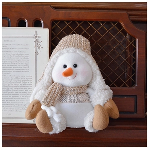 Detail of plush snowman toy with sequined knit hat next to a book in cozy home decor