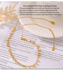 Detailed view of gold-plated PVD stainless steel necklace with beaded tassels on a book