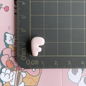 Miniature pink resin letter F charm shown on a scale measuring 1cm for DIY crafts