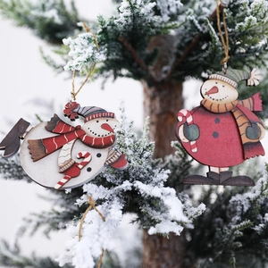 Wooden Christmas snowman door hanging decorations on a snowy tree branch