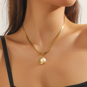 Gold moon pendant necklace with pearl on flat snake chain worn by a female model