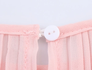 Detail of the pink chiffon dress back collar with white button closure and pleated fabric