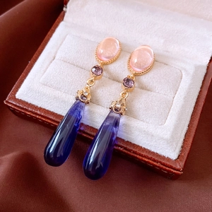 Close-up of vintage teardrop earrings with pink, purple, and blue crystals on velvet