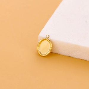Macro detail of oval gold stainless steel pendant with textured edges on stone base