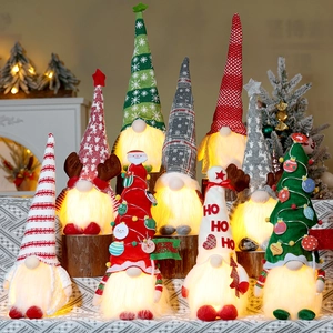 Close-up of glowing Christmas gnomes with LED lights and festive snowflake knit hats