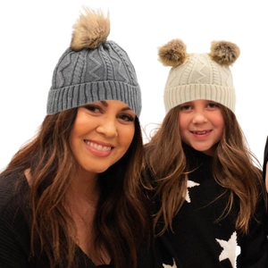Close-up of thick knit winter hats with fluffy faux fur pom-poms for warmth