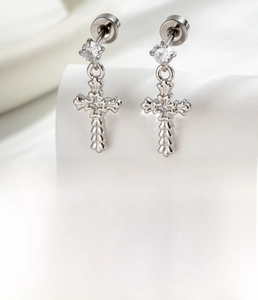 Detailed view of silver cross earring made of titanium steel, copper and zircon stones