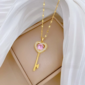Close-up of gold heart key pendant with pink gemstone and small zircon accents